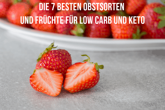 Im Vordergrund eine ganze und eine halbierte Erdbeere, im Hintergrund eine Schale mit vielen Erdbeeren