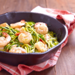 Zucchini-Nudeln mit Garnelen, angerichtet in einer Pfanne